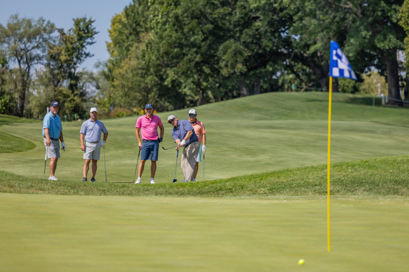 Group of golfers high-fiving on the course.